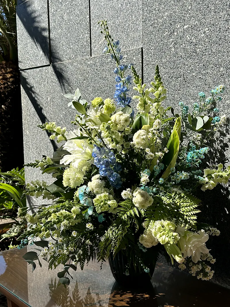 Arranjo de flores brancas e verdes junto a parede de pedra