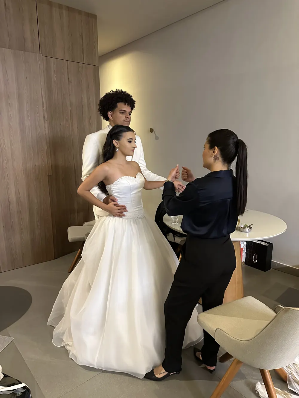 Assessora da Unità ajustando o vestido da noiva ao lado do noivo
