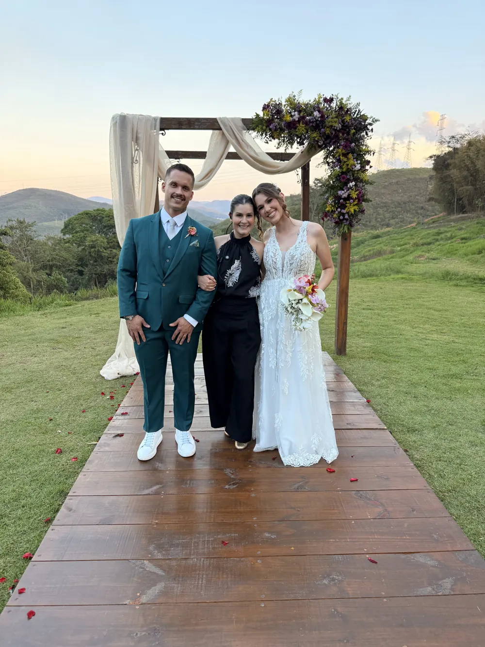 Bruna Dias com os noivos no deque ao pôr do sol